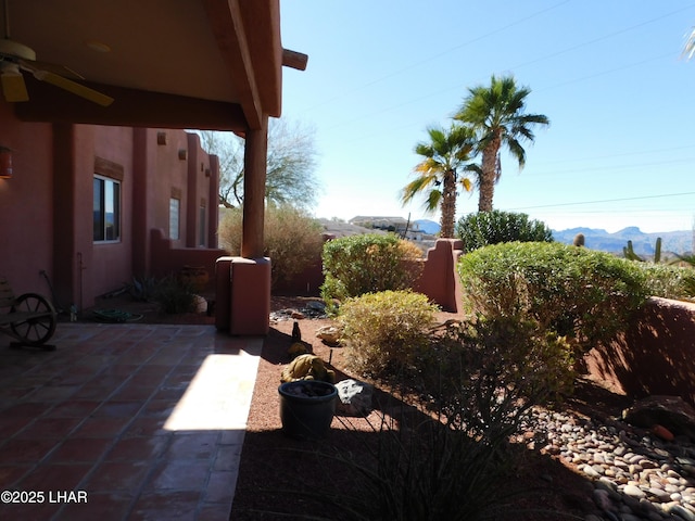 view of yard featuring a mountain view, ceiling fan, and a patio area