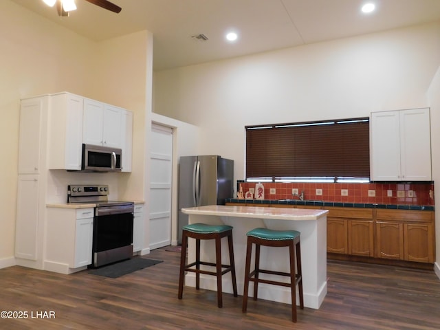 kitchen with backsplash, appliances with stainless steel finishes, a kitchen island, and white cabinets