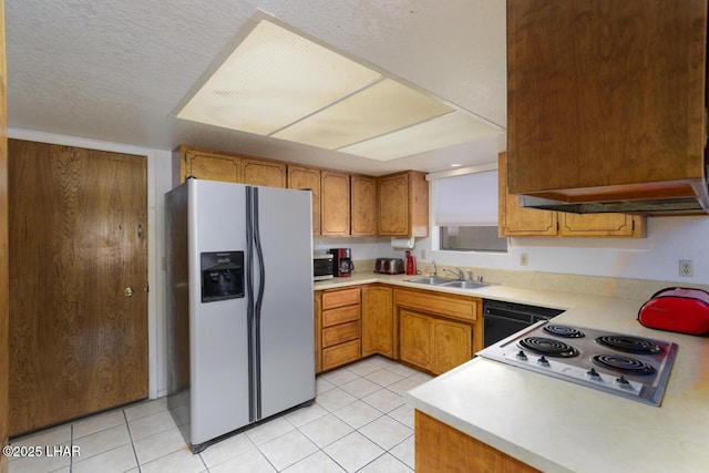 kitchen featuring light countertops, electric stovetop, stainless steel fridge, and a sink