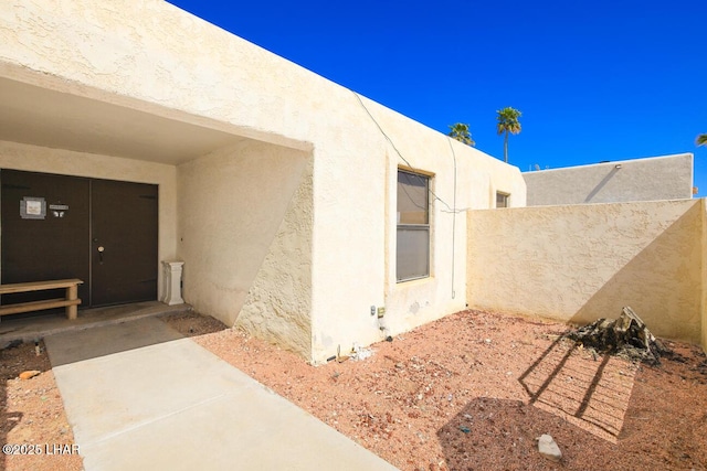 view of exterior entry featuring fence and stucco siding