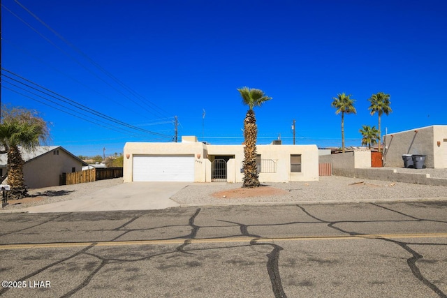 view of front facade with stucco siding, driveway, a garage, and fence