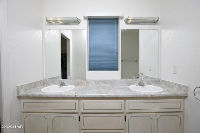 full bath with a sink, a wall mounted air conditioner, and double vanity