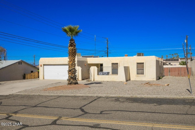 southwest-style home featuring a fenced front yard, stucco siding, driveway, and a garage