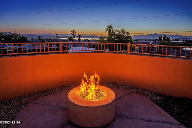 patio terrace at dusk with a fire pit and a water view