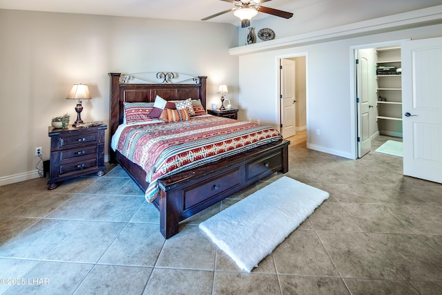 bedroom with a ceiling fan, a walk in closet, baseboards, and light tile patterned floors