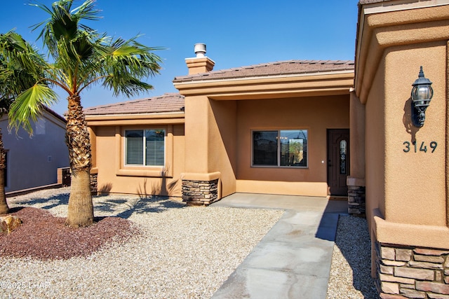 entrance to property featuring a patio, a tiled roof, and stucco siding