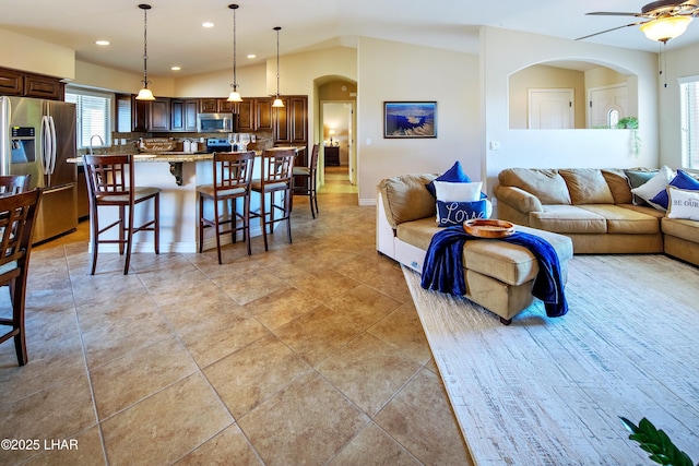 living room with light tile patterned floors, arched walkways, ceiling fan, vaulted ceiling, and recessed lighting