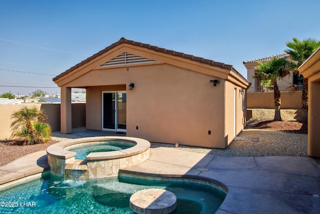 back of property with a pool with connected hot tub, a tiled roof, fence, and stucco siding