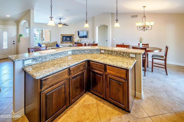 kitchen with arched walkways, light tile patterned flooring, a kitchen island, open floor plan, and pendant lighting