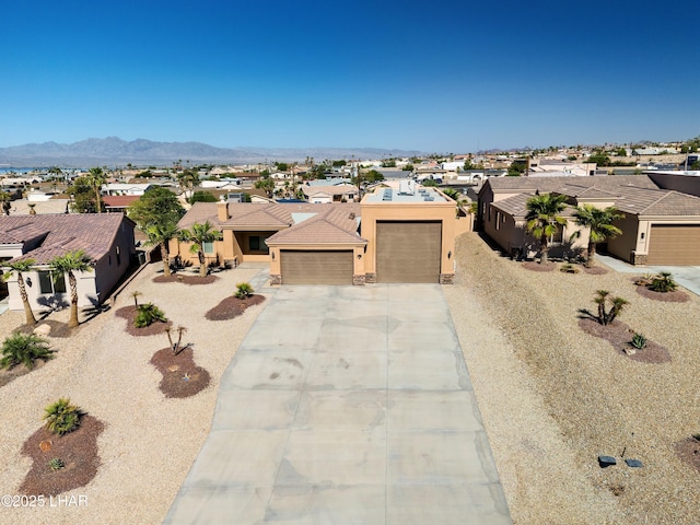 view of front of house featuring stucco siding, a mountain view, a garage, a residential view, and driveway