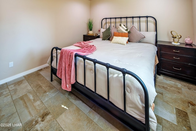 bedroom with baseboards and stone tile floors