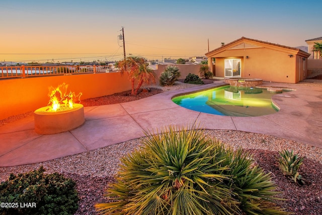 view of swimming pool with a pool with connected hot tub, a patio area, a fenced backyard, and a fire pit