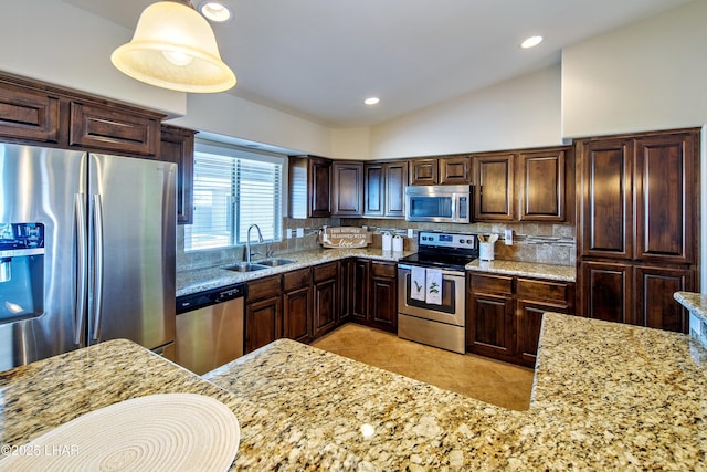 kitchen featuring appliances with stainless steel finishes, backsplash, a sink, and pendant lighting