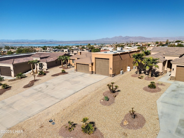 view of front of home with concrete driveway, a residential view, an attached garage, a mountain view, and stucco siding