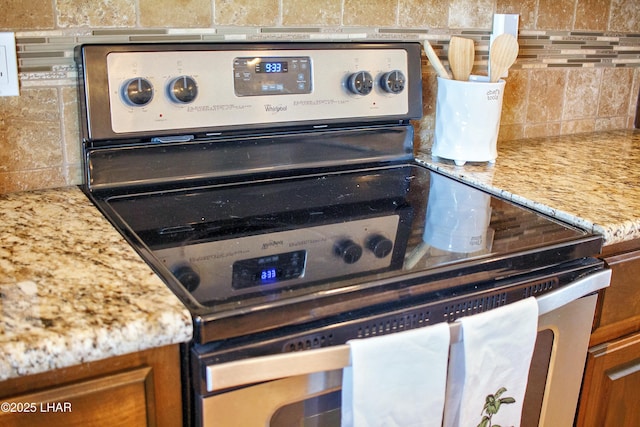 interior details with light stone countertops, decorative backsplash, stainless steel range with electric stovetop, and brown cabinets