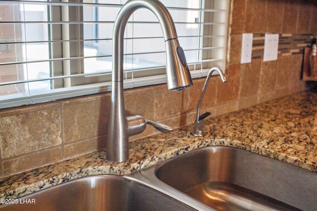 details featuring stone counters, backsplash, and a sink