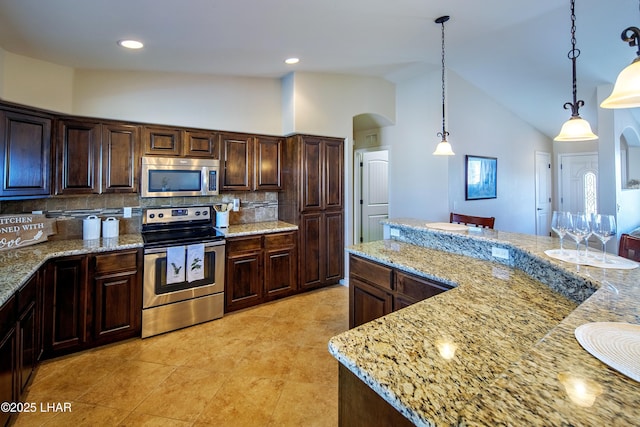 kitchen featuring arched walkways, appliances with stainless steel finishes, light stone countertops, tasteful backsplash, and decorative light fixtures