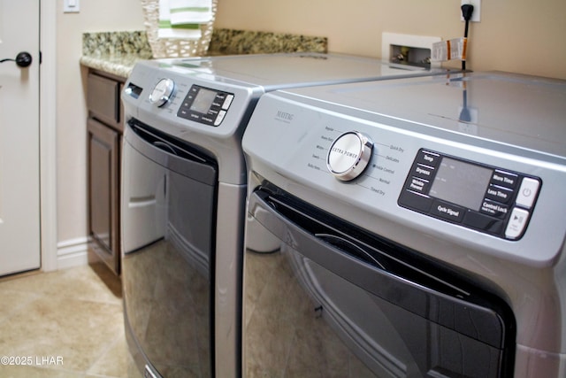 clothes washing area featuring cabinet space and washer and clothes dryer