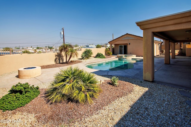 view of swimming pool with a pool with connected hot tub, a fenced backyard, a fire pit, and a patio