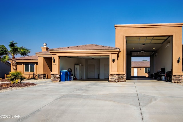 view of front of property with central AC unit, an attached garage, stone siding, driveway, and stucco siding