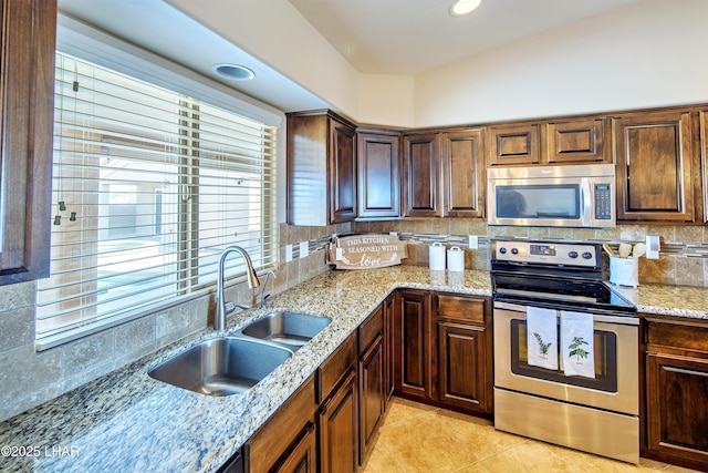 kitchen with light stone countertops, tasteful backsplash, appliances with stainless steel finishes, and a sink