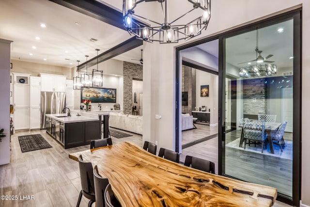 dining space featuring sink, ceiling fan with notable chandelier, and light hardwood / wood-style floors