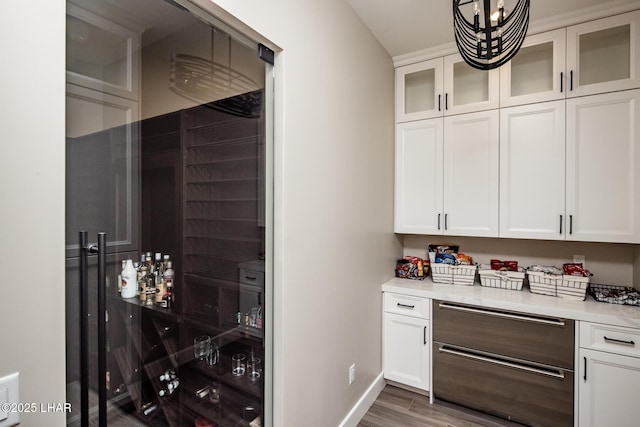 bar featuring light stone counters, a notable chandelier, dark wood-type flooring, and white cabinets