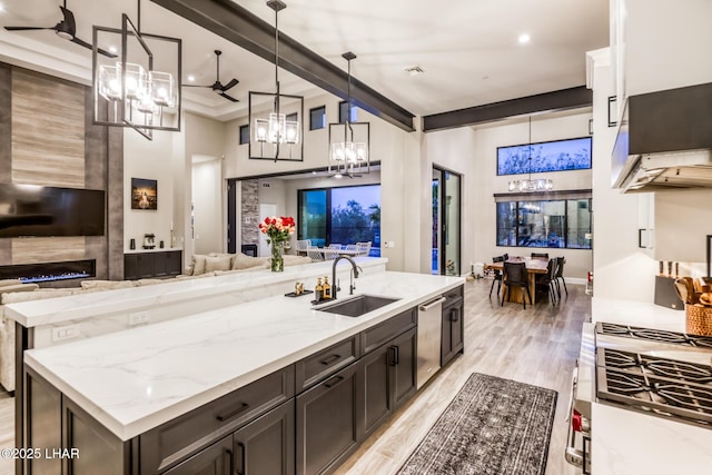 kitchen featuring pendant lighting, sink, a center island, light stone counters, and light wood-type flooring