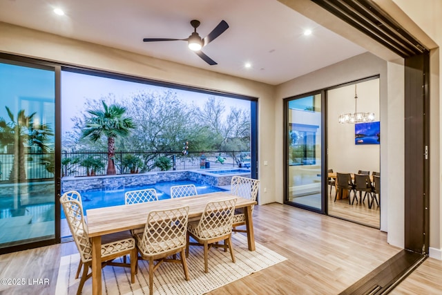 dining area with ceiling fan with notable chandelier and light hardwood / wood-style floors