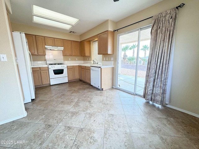 kitchen with under cabinet range hood, white appliances, light countertops, and baseboards