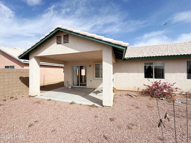 rear view of house featuring a patio, fence, and stucco siding