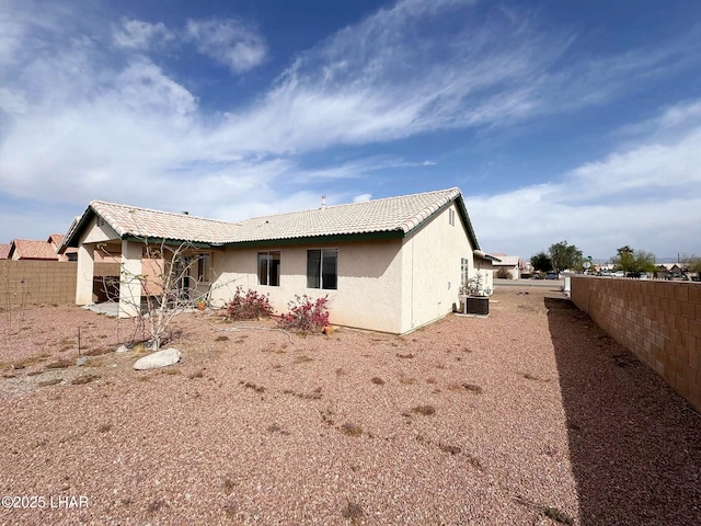 back of house featuring stucco siding, cooling unit, a tile roof, and fence