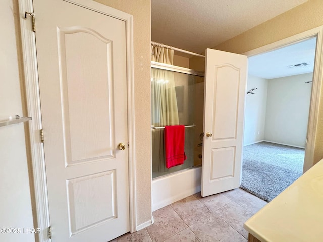 bathroom featuring tile patterned flooring, visible vents, a textured ceiling, and enclosed tub / shower combo