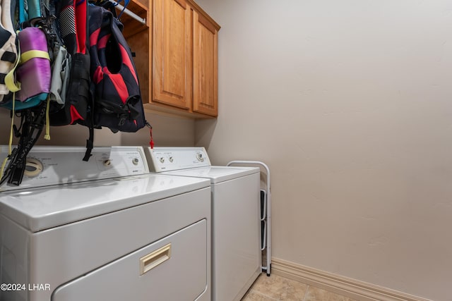 clothes washing area featuring cabinets, washer and dryer, and light tile patterned floors