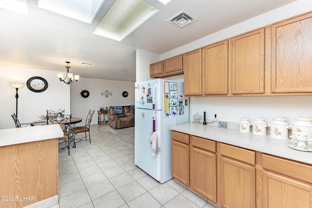 kitchen featuring light tile patterned flooring, a chandelier, hanging light fixtures, a textured ceiling, and white fridge