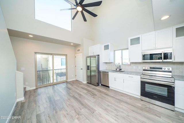 kitchen with sink, appliances with stainless steel finishes, white cabinetry, a wealth of natural light, and decorative backsplash