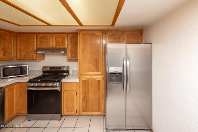 2130 Smoketree Ave N, Lake Havasu City, AZ 86403 - kitchen featuring light tile patterned flooring, light countertops, brown cabinets, stainless steel appliances, and under cabinet range hood