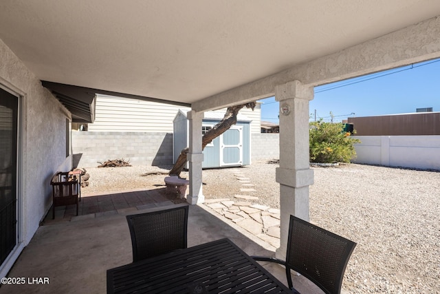 2130 Smoketree Ave N, Lake Havasu City, AZ 86403 - view of patio / terrace with a storage unit, outdoor dining space, a fenced backyard, and an outbuilding
