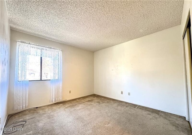 carpeted empty room featuring a textured ceiling