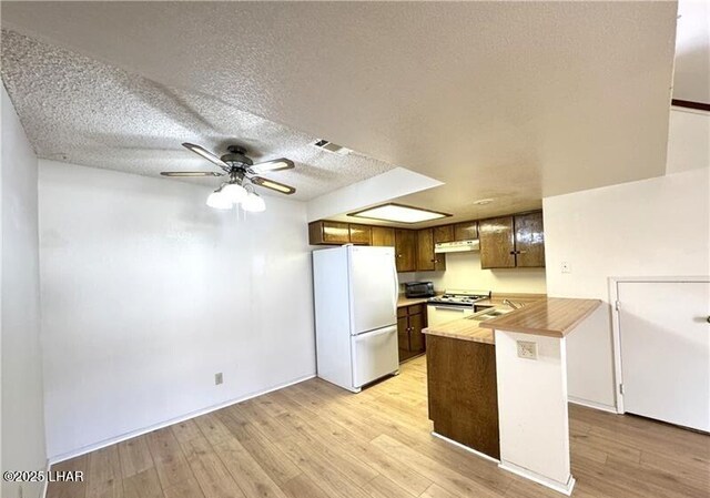 kitchen featuring sink, white appliances, ceiling fan, a textured ceiling, and kitchen peninsula