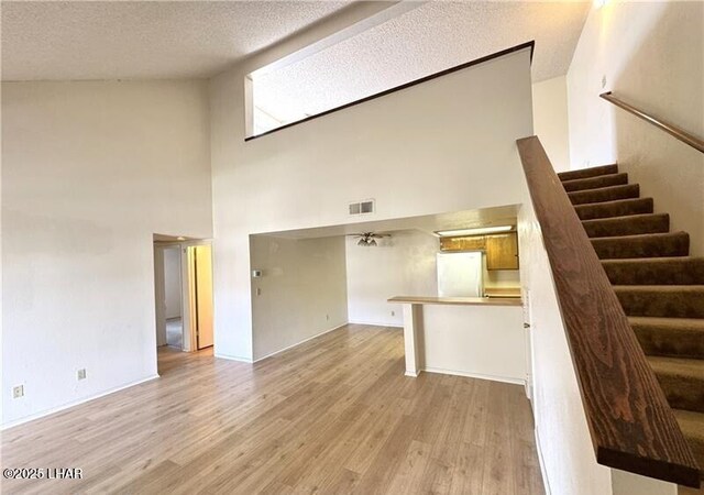 unfurnished living room with vaulted ceiling, light colored carpet, and a textured ceiling