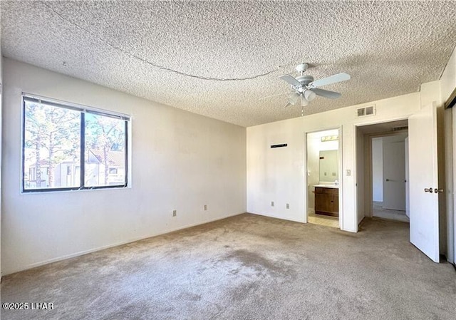 unfurnished bedroom featuring connected bathroom, light carpet, and a textured ceiling