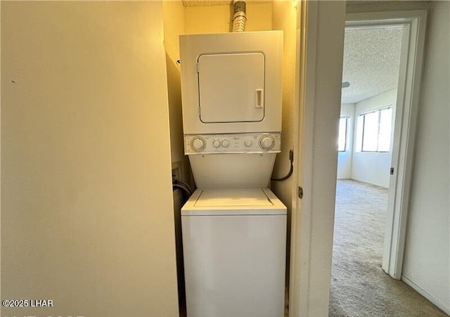 clothes washing area featuring stacked washer and dryer, carpet floors, and a textured ceiling