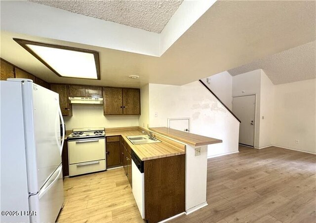 kitchen with white appliances, kitchen peninsula, and sink