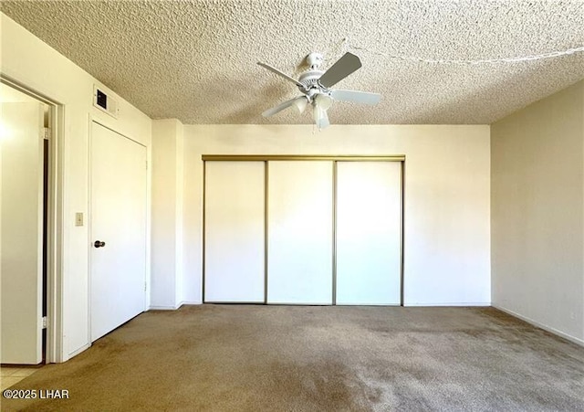 unfurnished bedroom with light carpet, ceiling fan, a closet, and a textured ceiling