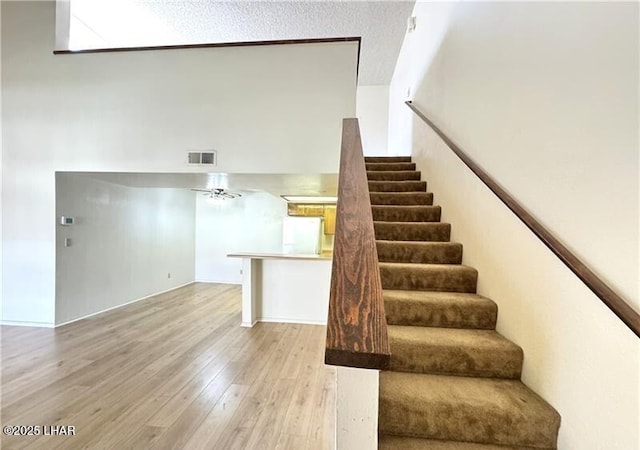 unfurnished living room with carpet floors, a textured ceiling, and a high ceiling