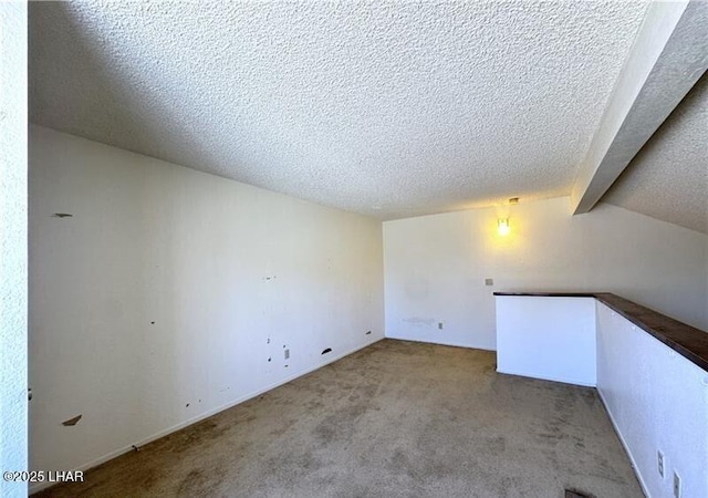 carpeted spare room with lofted ceiling with beams and a textured ceiling