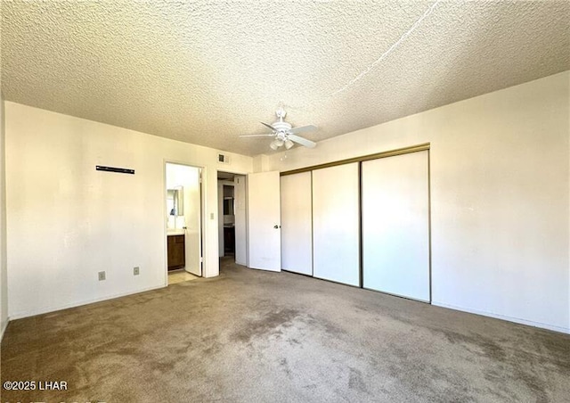 unfurnished bedroom with ensuite bathroom, carpet floors, ceiling fan, a textured ceiling, and a closet