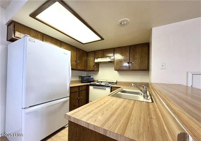 kitchen featuring light carpet, a textured ceiling, kitchen peninsula, white fridge, and ceiling fan