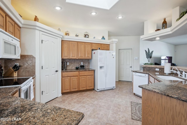 kitchen featuring white appliances, tasteful backsplash, dark stone countertops, a sink, and recessed lighting